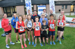 Wendy Percey of Lesley Shand Funeral Directors, centre, and Garry Dickerson of Seyward Window Ltd, blue top, and Cllr Paul Harrison representing the Corfe Mullen Parish Council with the winners of the Corfe Mullen 5K and children’s one mile run.