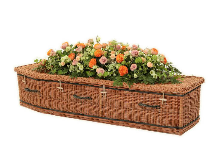 A Somerset Willow coffin with black band and flower arrangement.