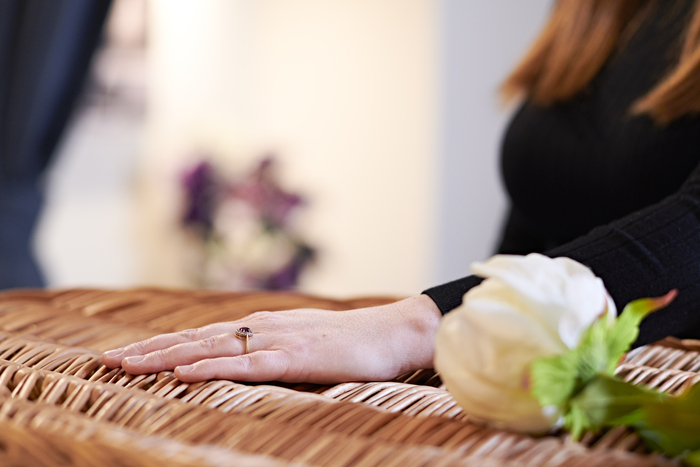 Woman with hand on casket.