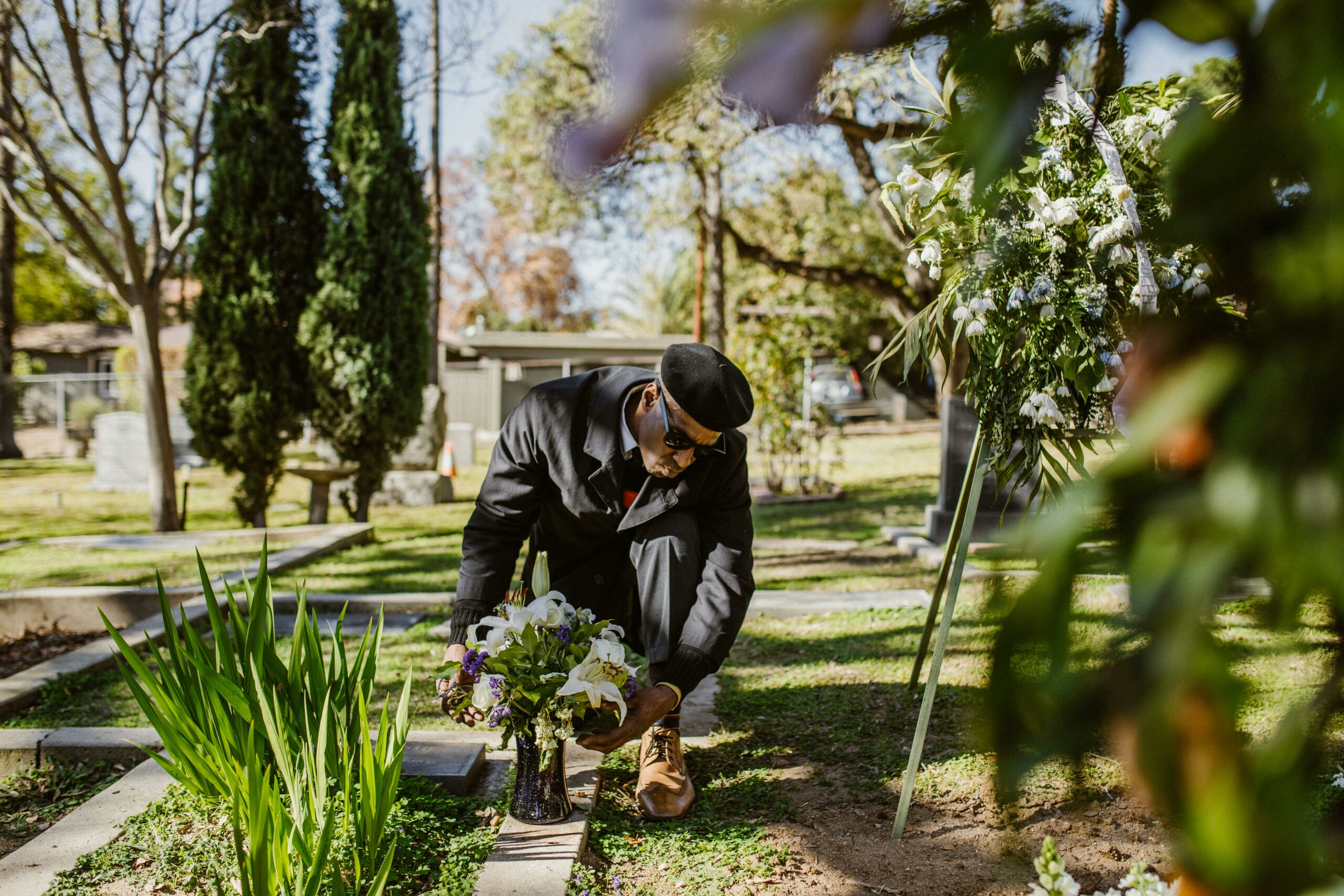 Man arranging flowers in a vase on a burial ground.